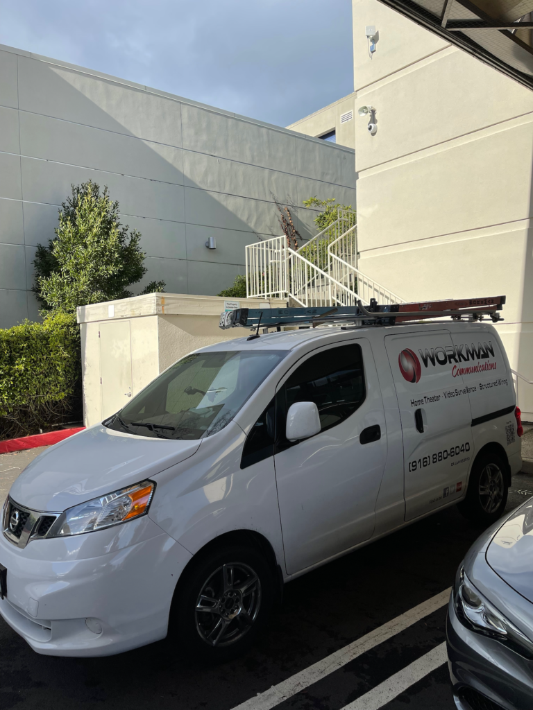 A white van is parked in a parking lot in front of a building.