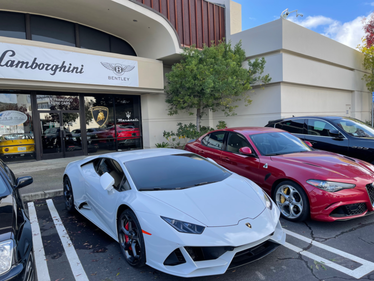 A white lamborghini is parked in front of a building