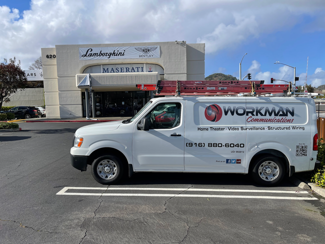 A white workman van is parked in front of a building.