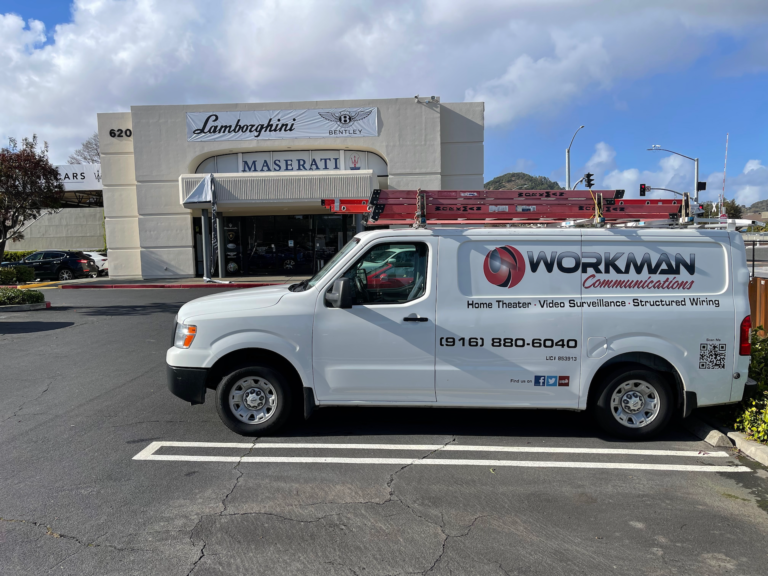 A white workman van is parked in front of a maserati building.