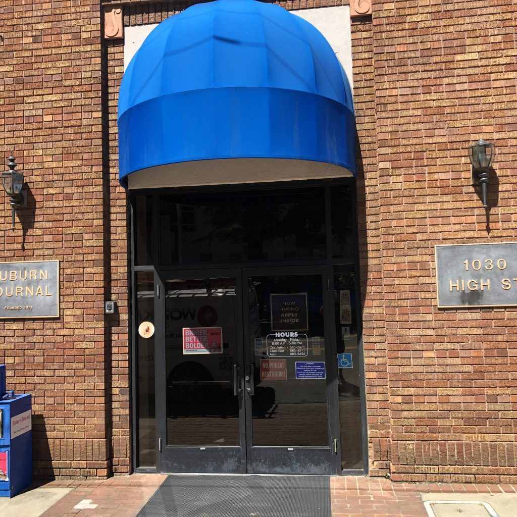 A brick building with a blue awning over the entrance