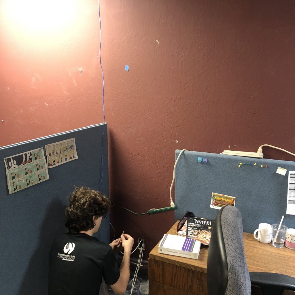 A man is sitting in a cubicle in front of a desk.