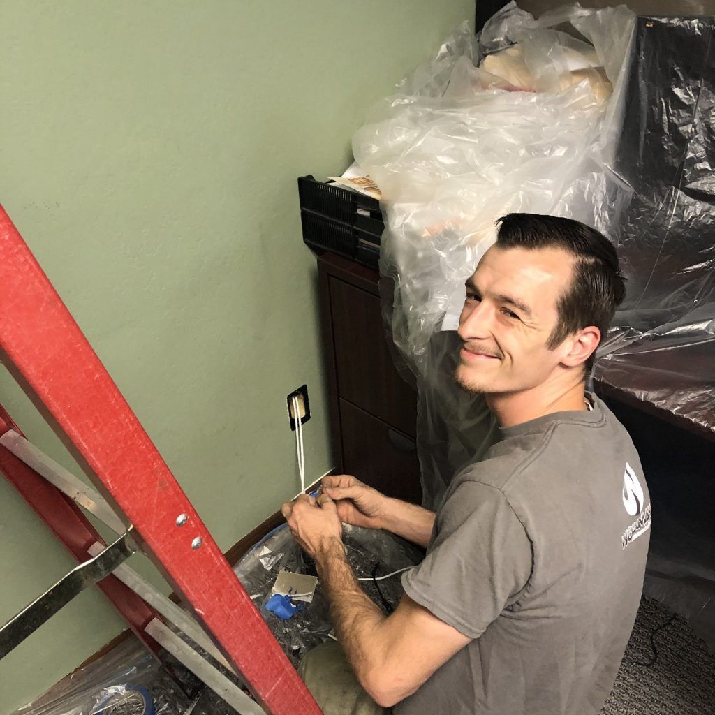 A man is standing next to a red ladder in a room.