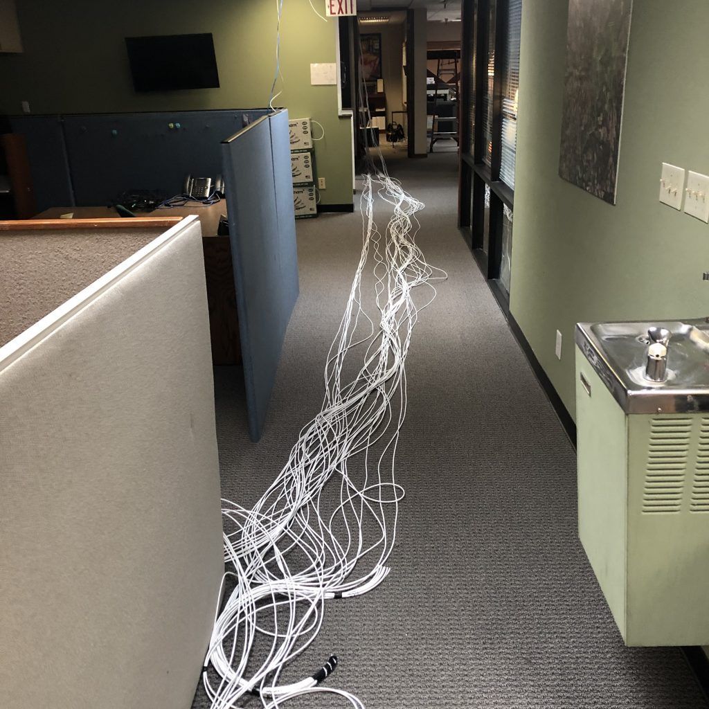 A hallway with a water fountain and a bunch of wires on the floor