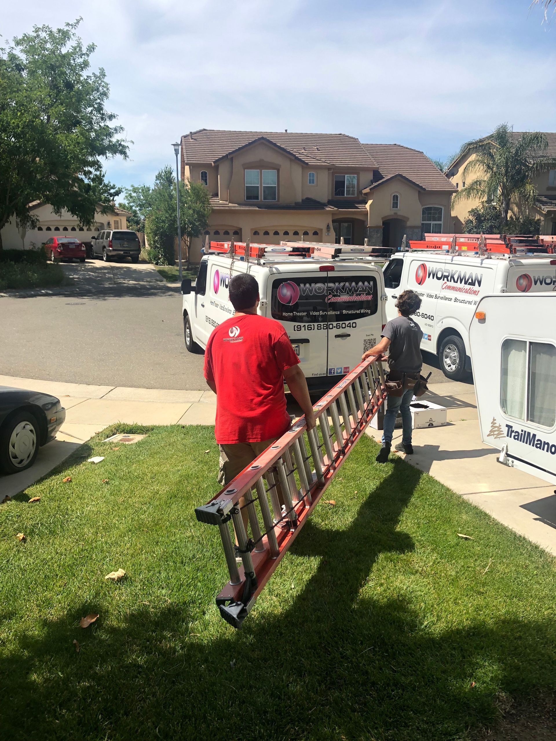 A man in a red shirt is carrying a ladder