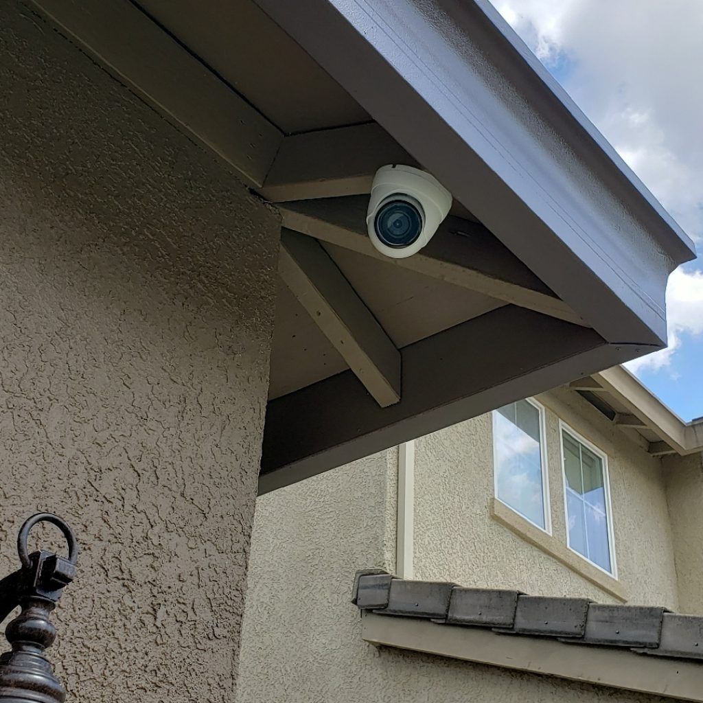 A security camera is mounted on the side of a house.