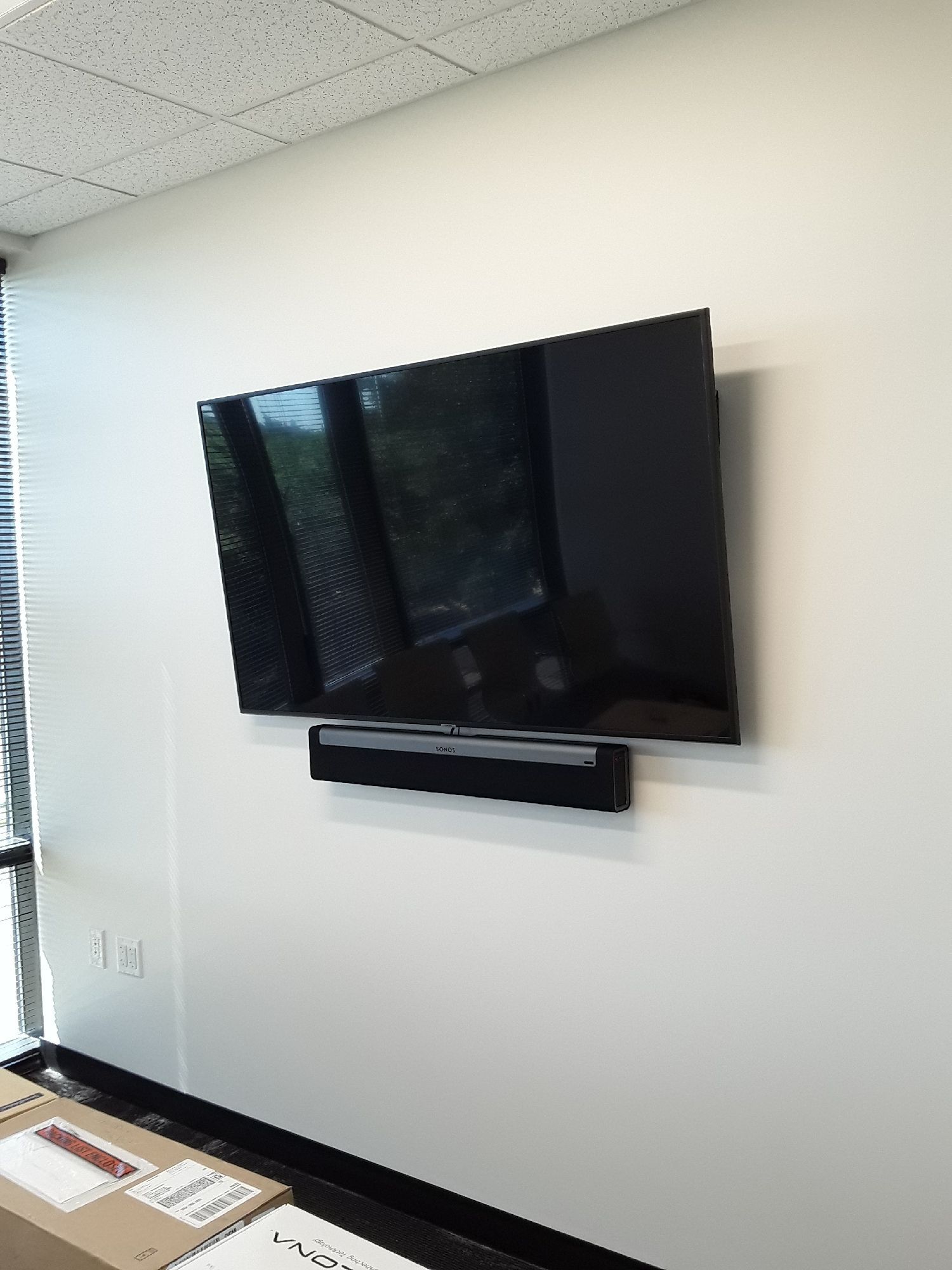 A flat screen tv is mounted on a wall next to a window.