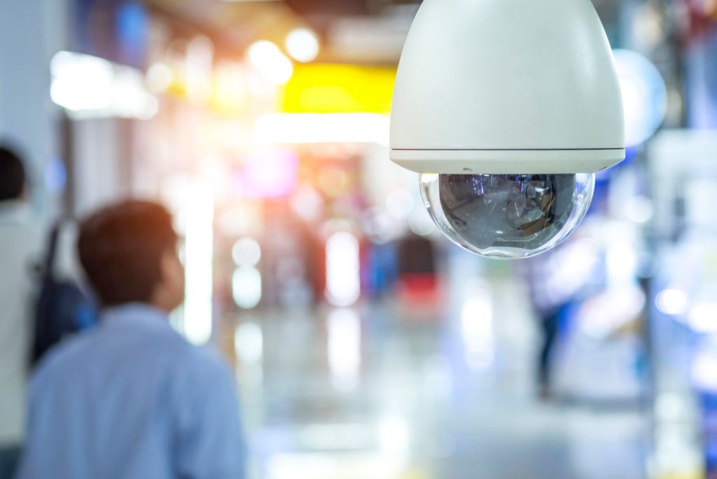 A security camera is hanging from the ceiling in a mall.