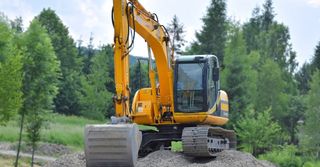 A yellow excavator is sitting on top of a pile of gravel.