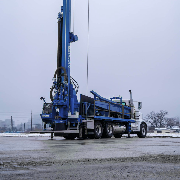 Un camion bleu avec une grue à l'arrière est garé sur un parking