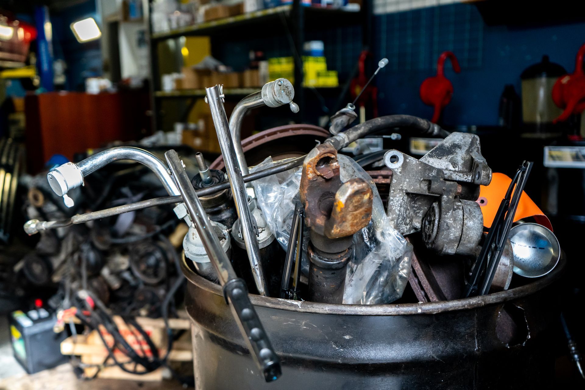 A bucket filled with a bunch of rusty metal parts in a garage.