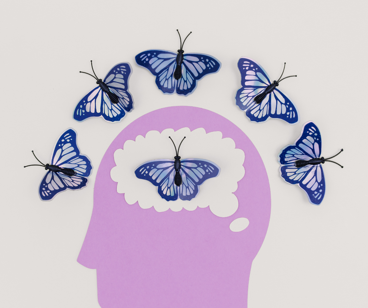 Purple silhouette head with a brain-shaped thought bubble containing a butterfly; six blue butterflies arch above.