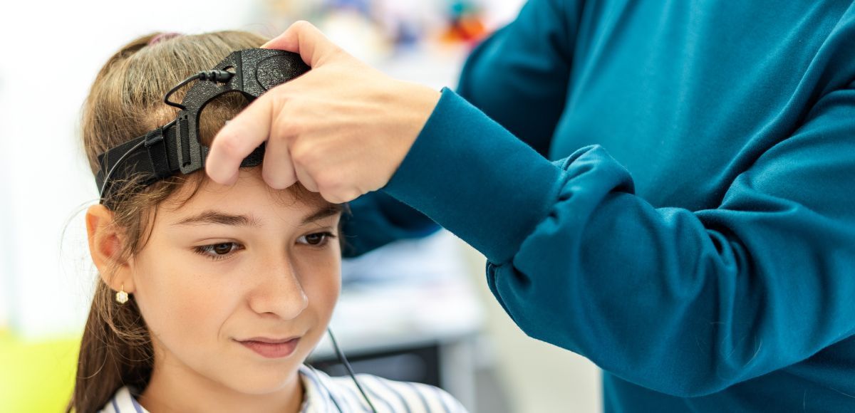 A clinician adjusts a cap on a child’s head during a medical procedure