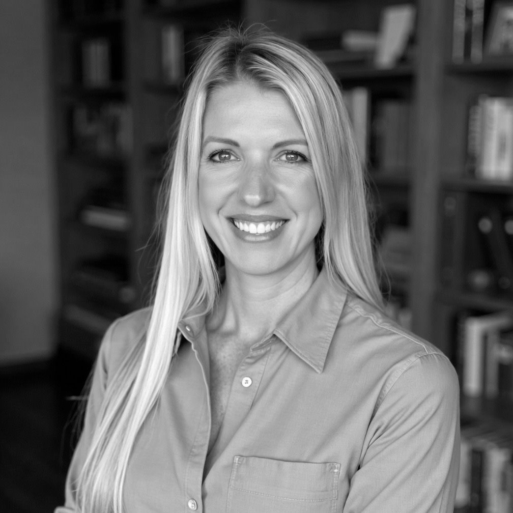 Sarah Whatley in a button-up shirt standing in front of bookshelves