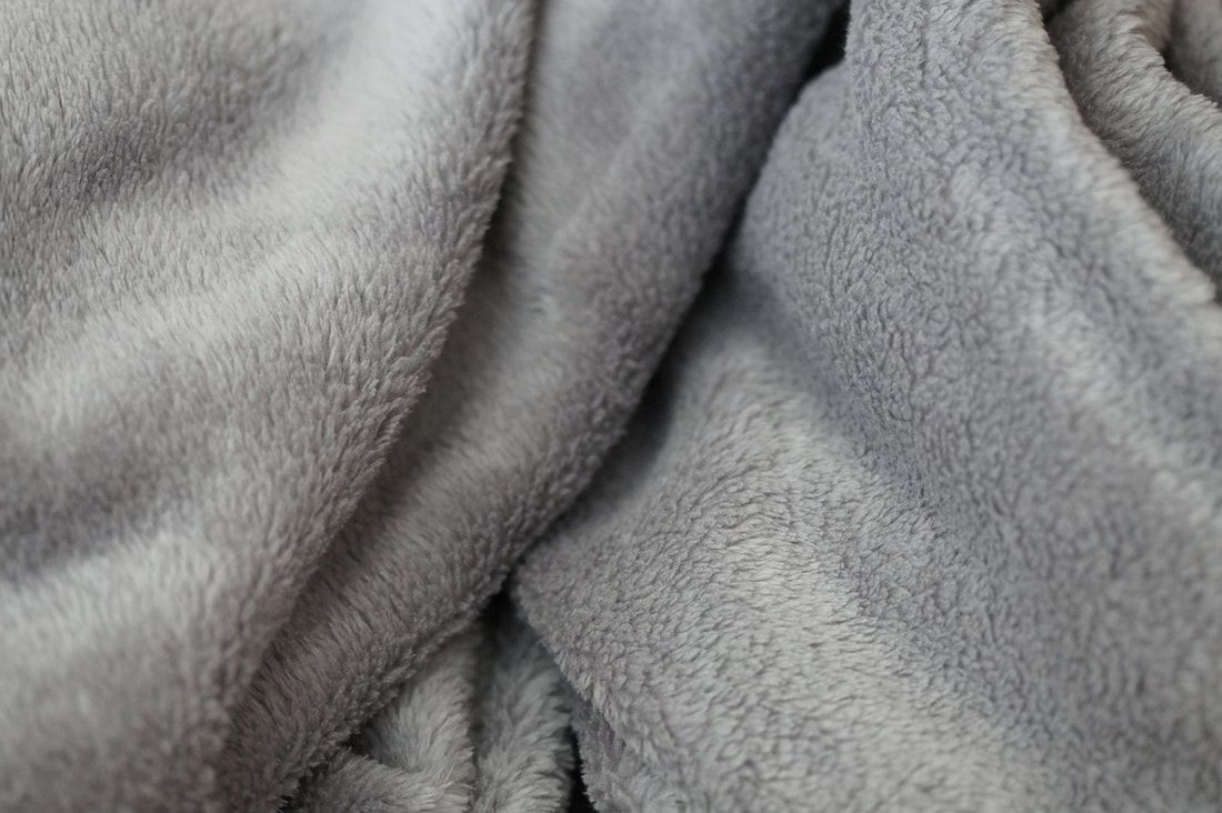 Gray, plush blanket with soft, fuzzy texture and folds.