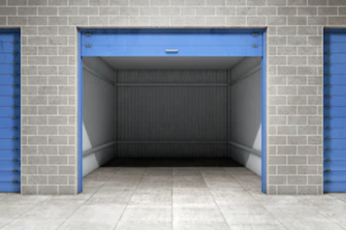 Open blue storage unit in a brick building, empty interior, surrounded by closed blue units.