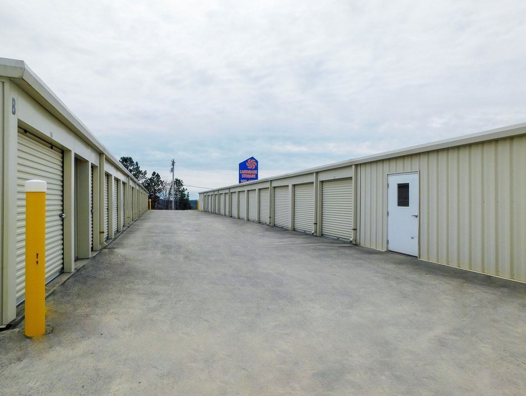 Storage units along a concrete driveway under a cloudy sky.
