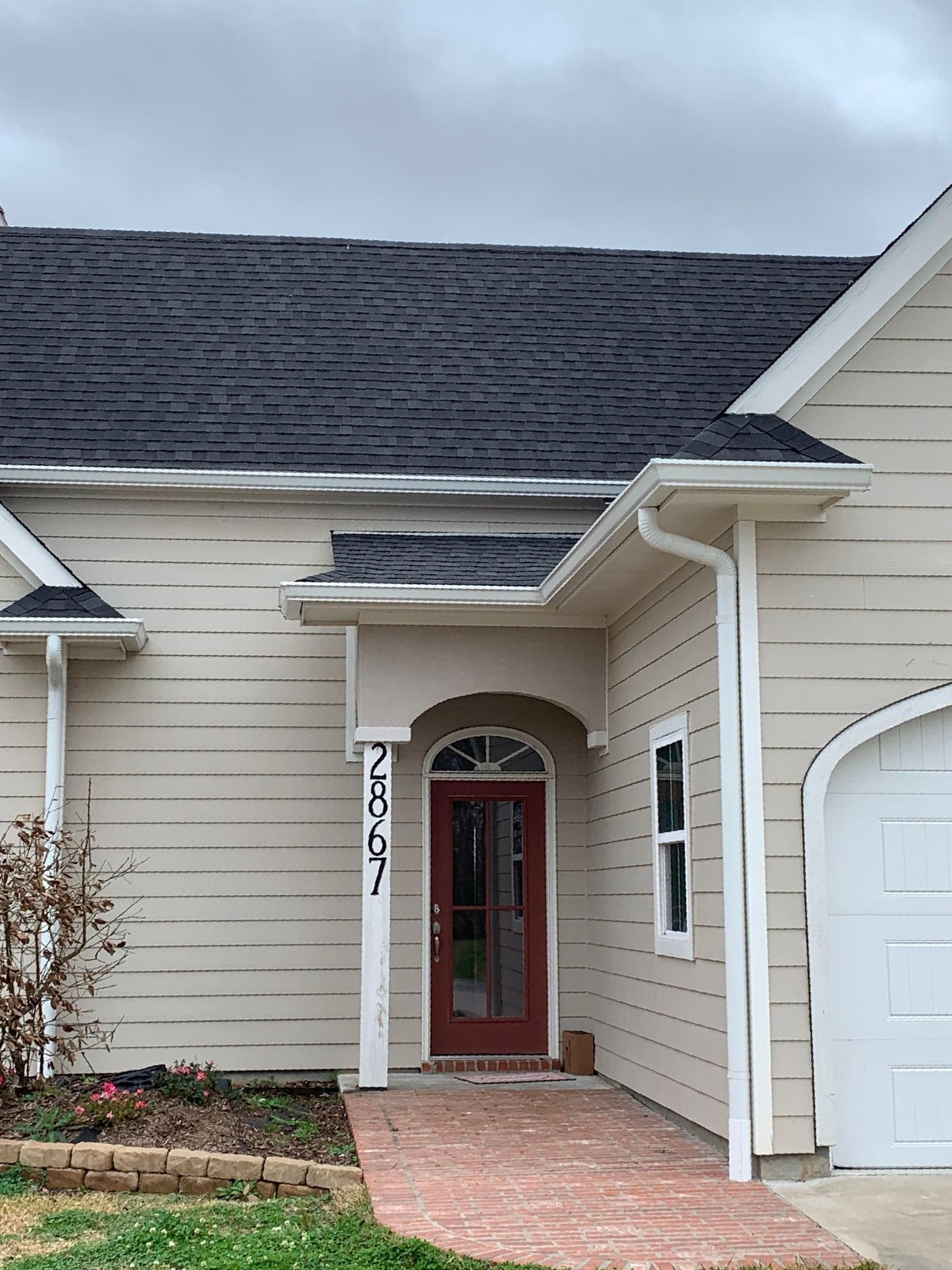 A white house with a black roof and a red door
