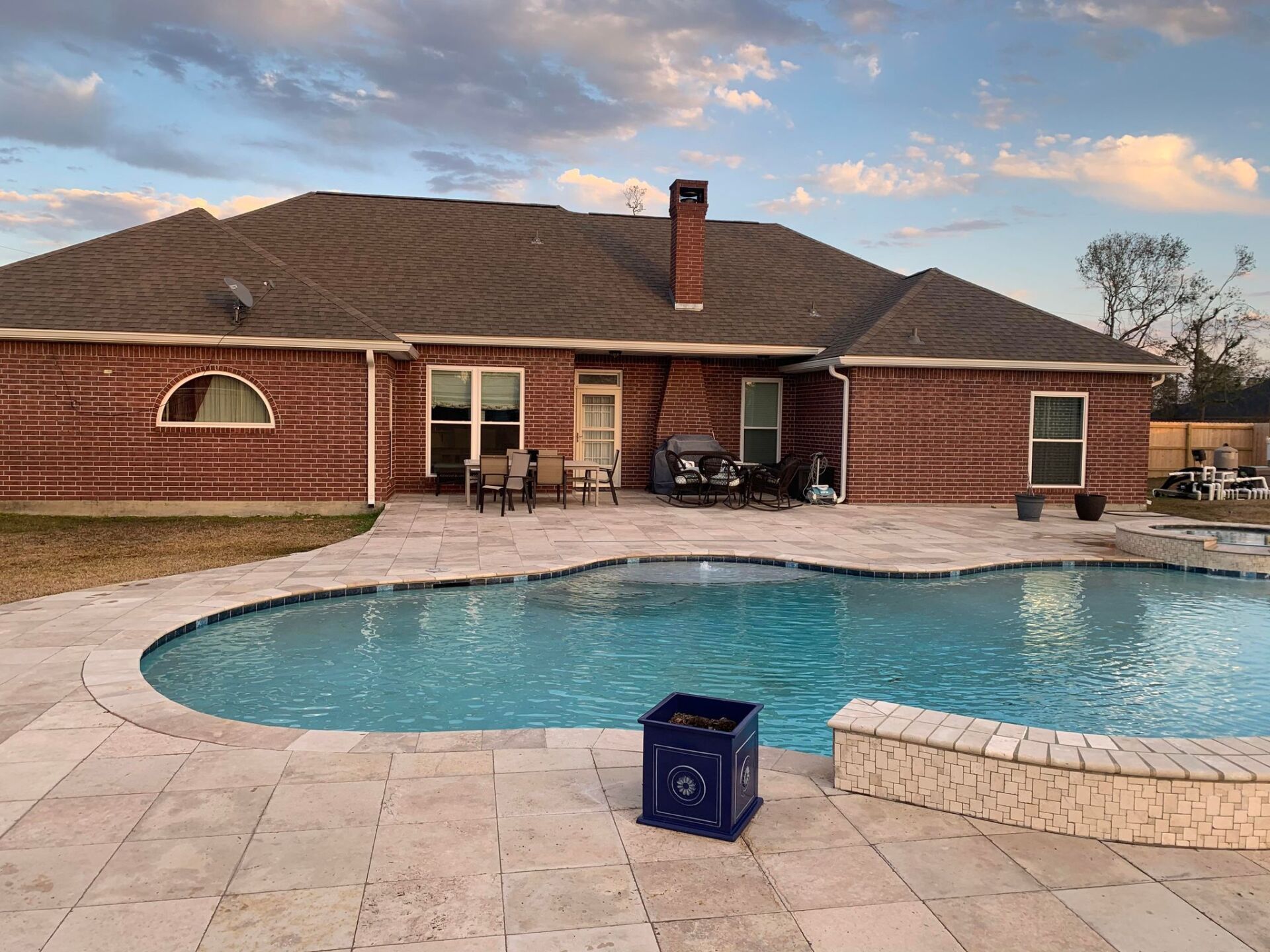 A large brick house with a large swimming pool in front of it.