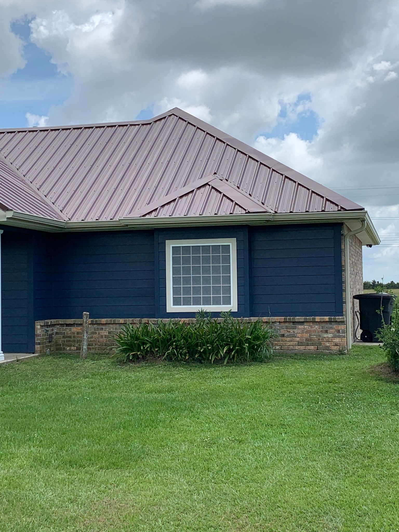 A blue house with a purple roof is sitting on top of a lush green field.