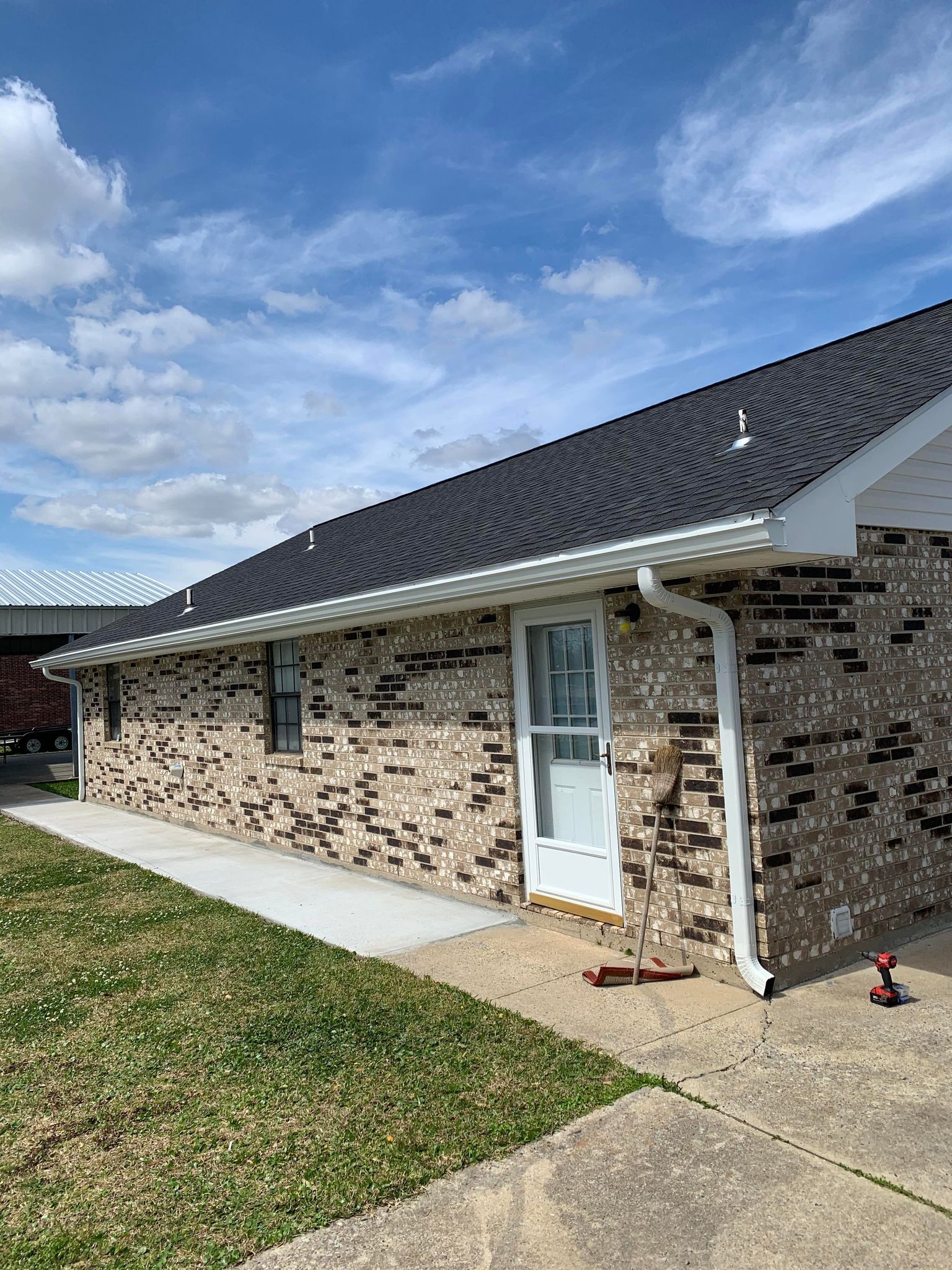 A brick house with a black roof and a white door.
