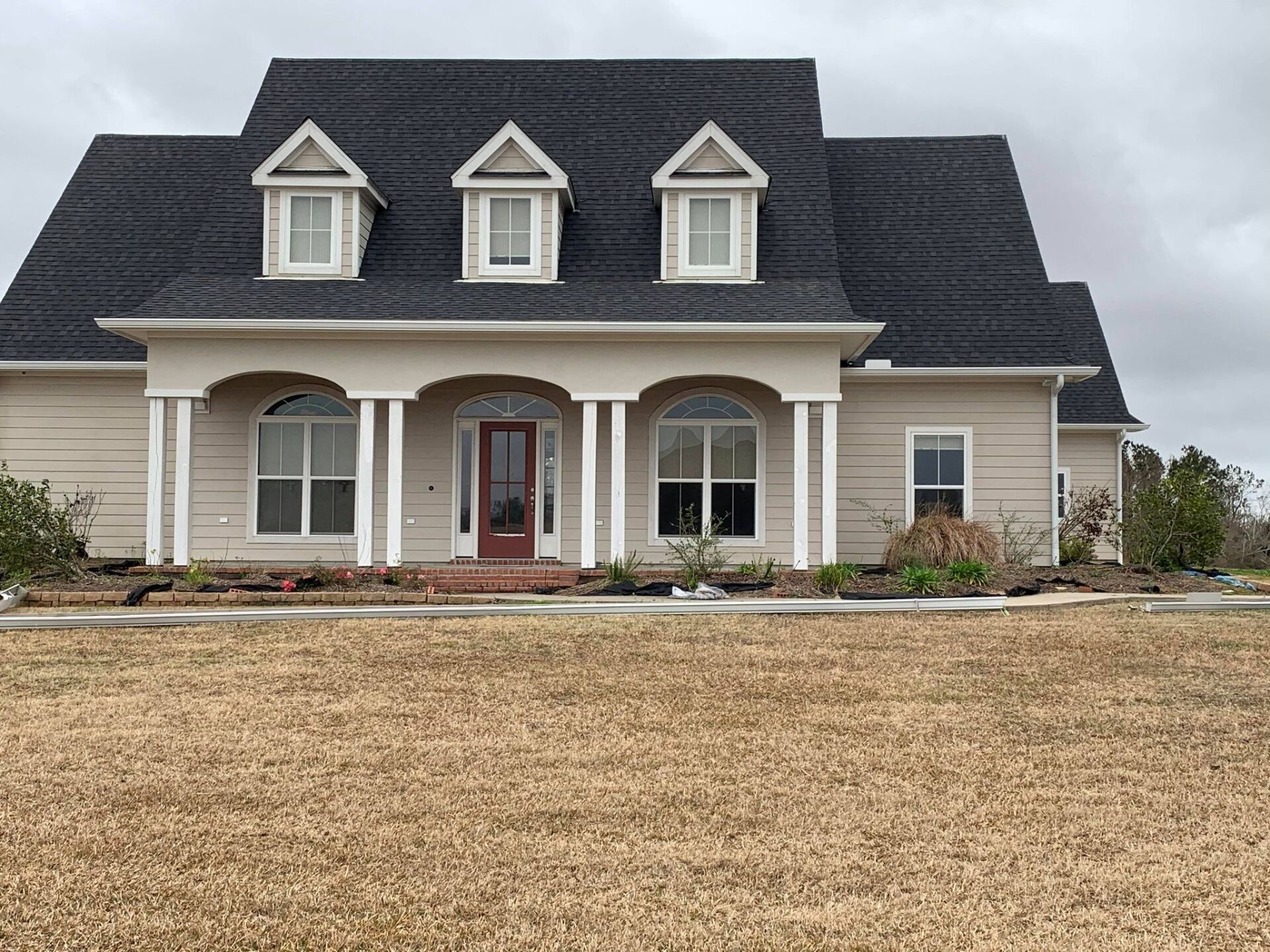 A large house with a black roof is sitting in the middle of a field.