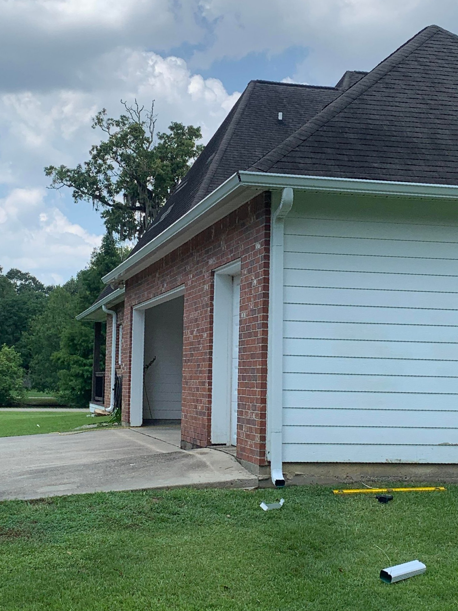 A brick house with a white garage door and a black roof.
