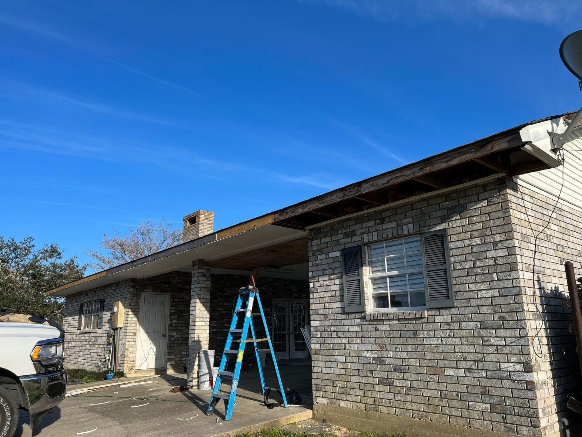 A ladder is sitting in front of a brick house.