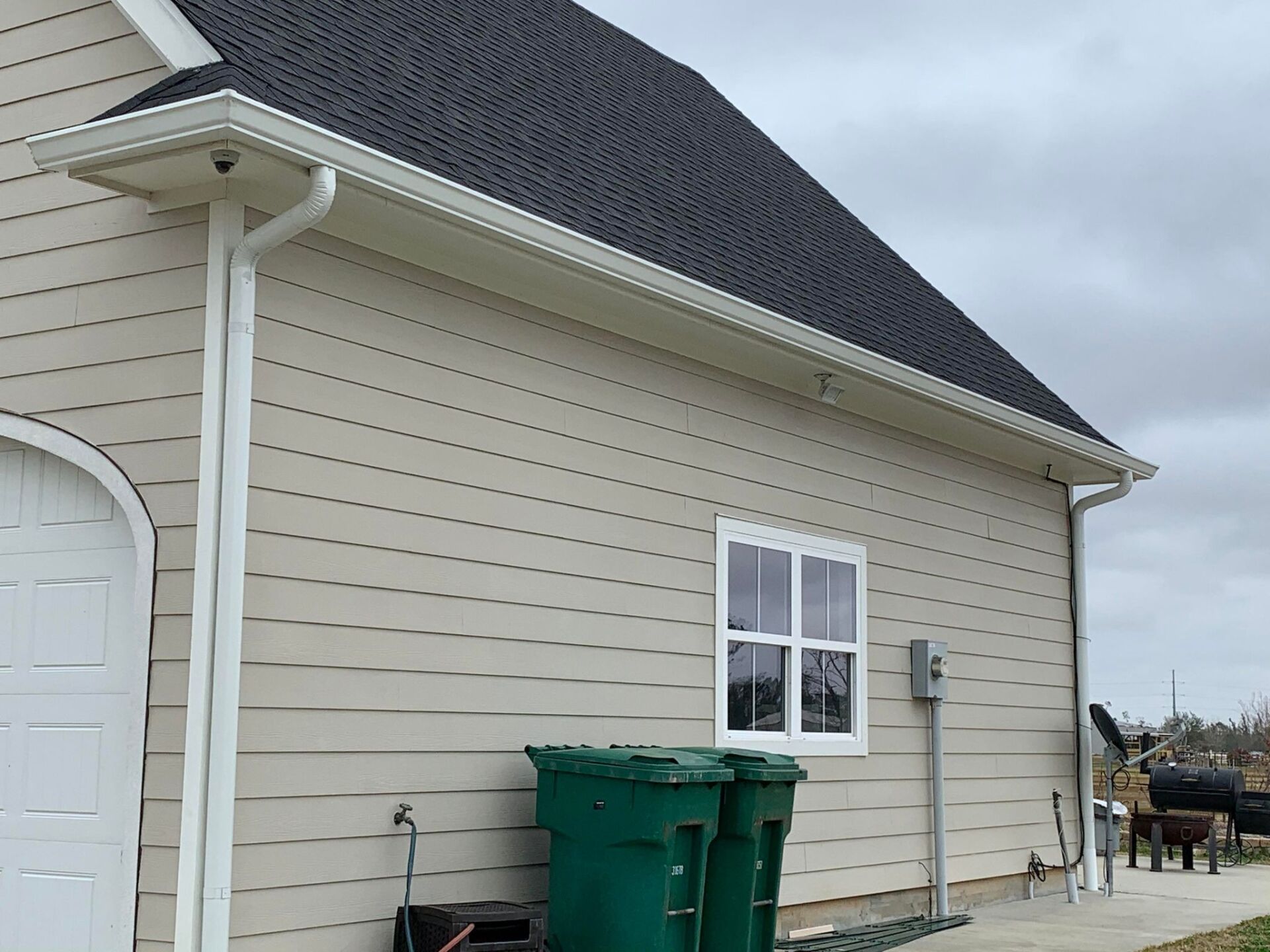 A house with two green trash cans on the side of it