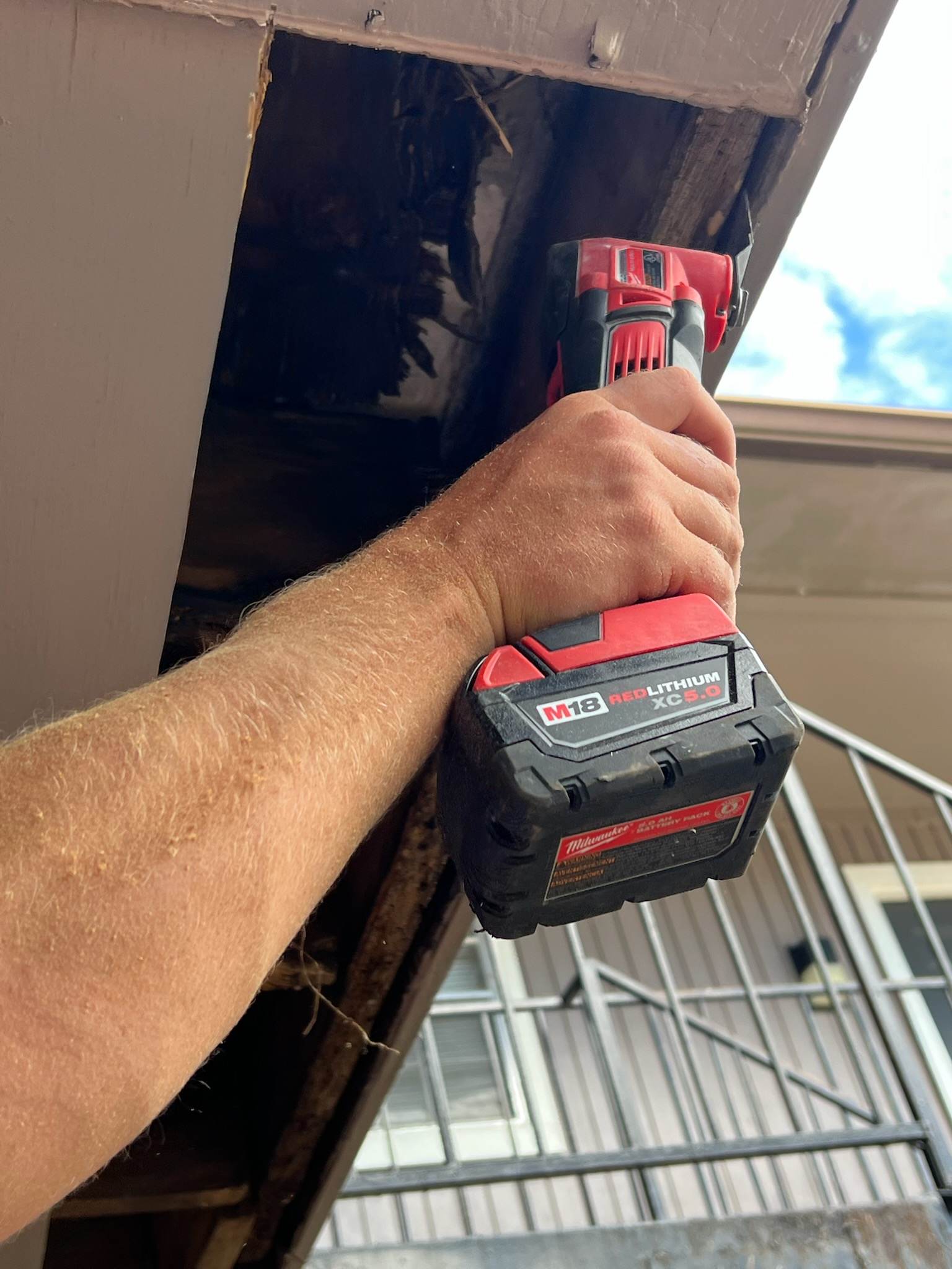 A person is using a cordless drill on a roof.