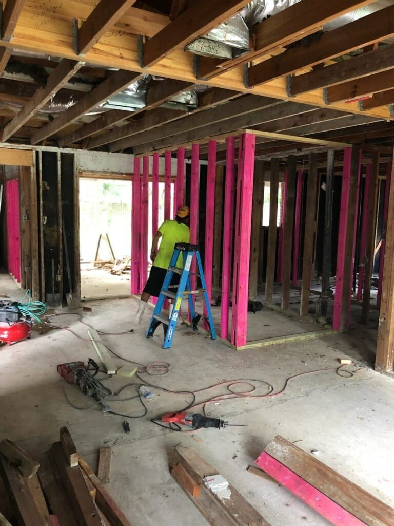 A man is standing on a ladder in a room under construction.