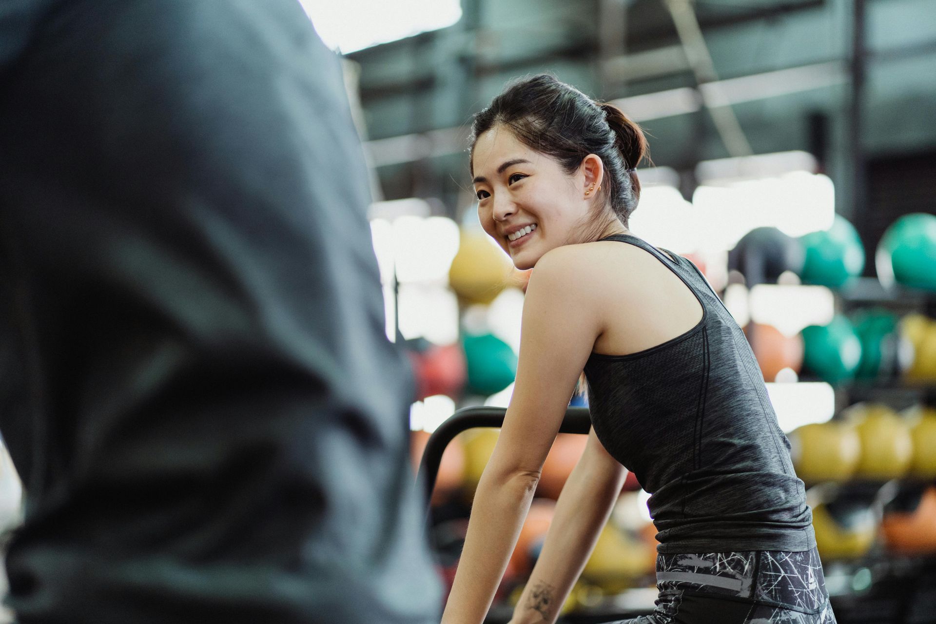 Woman in a gym smiling over her shoulder near colorful dumbbells