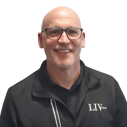 Smiling bald man in glasses wearing a black jacket with a logo, against a white background