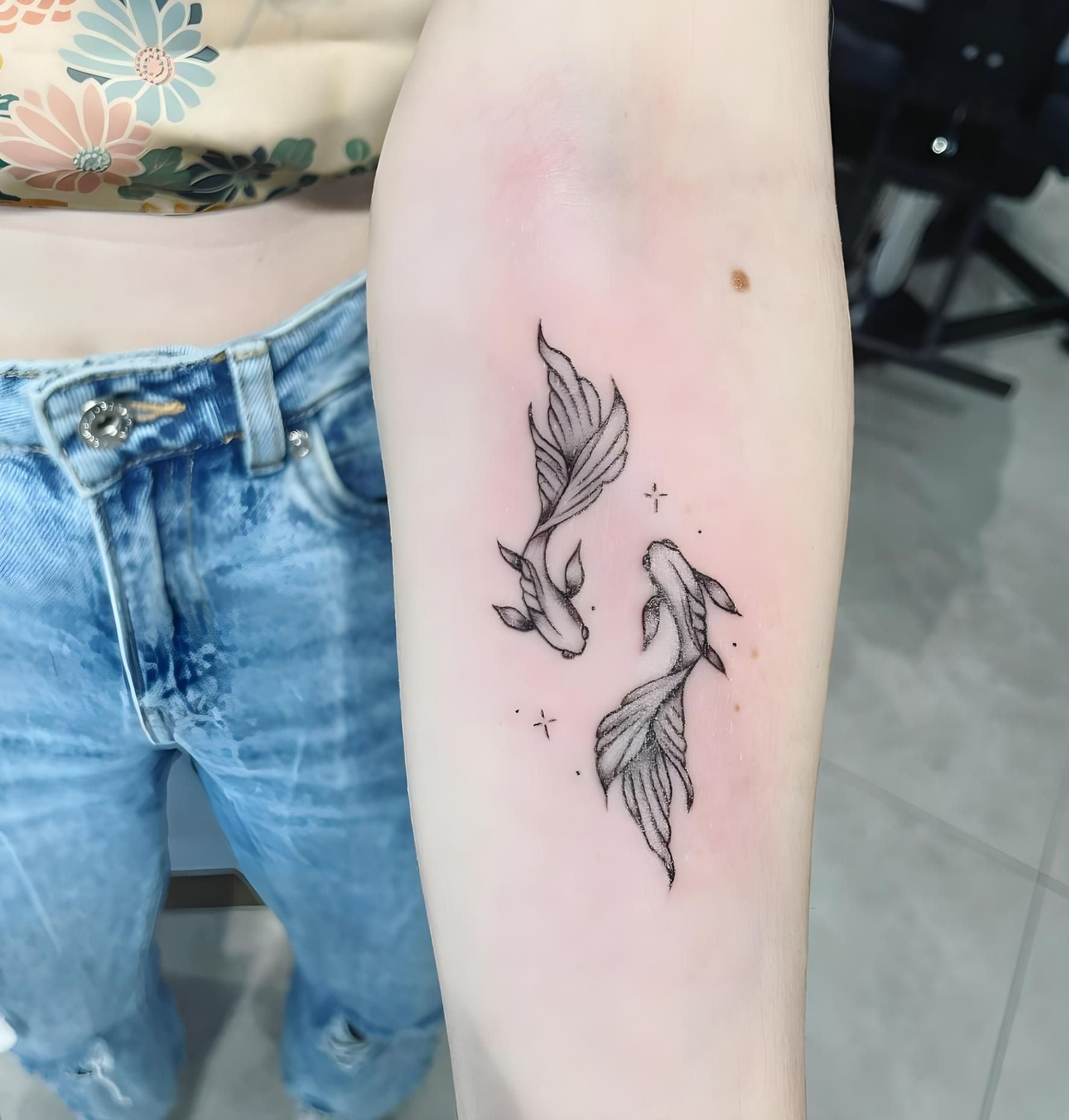 Two black line art koi fish tattoo on a person's arm, with two small stars — Tattoo Inc Studio In Broadbeach, QLD