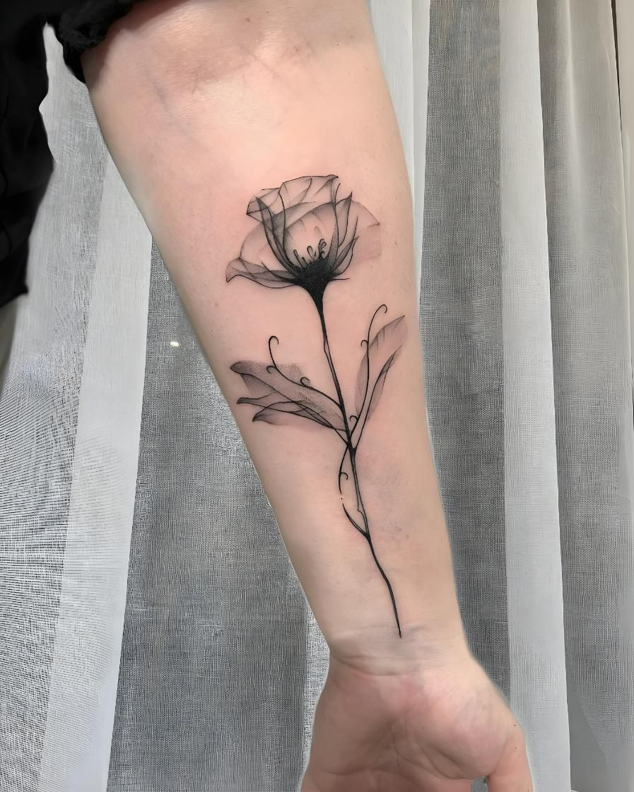 Tattoo of a black and gray flower, with a stem and leaves, on a forearm — Tattoo Inc Studio In Broadbeach, QLD