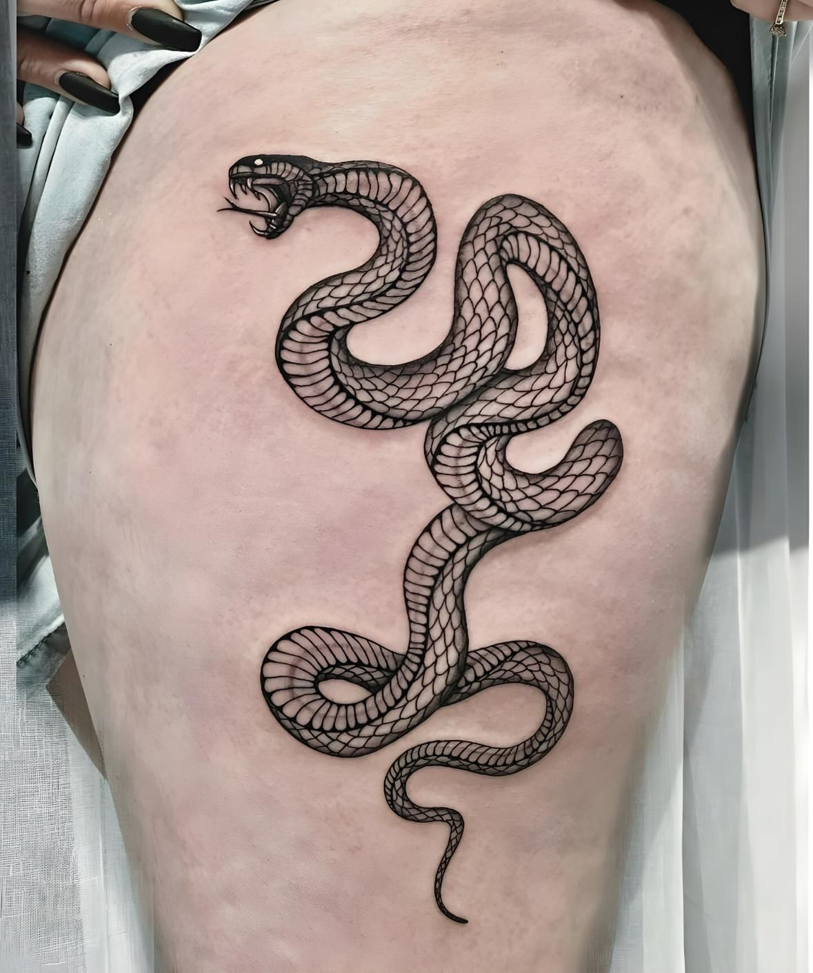 Black snake tattoo on thigh, detailed scales, open mouth, coiled pose — Tattoo Inc Studio In Broadbeach, QLD