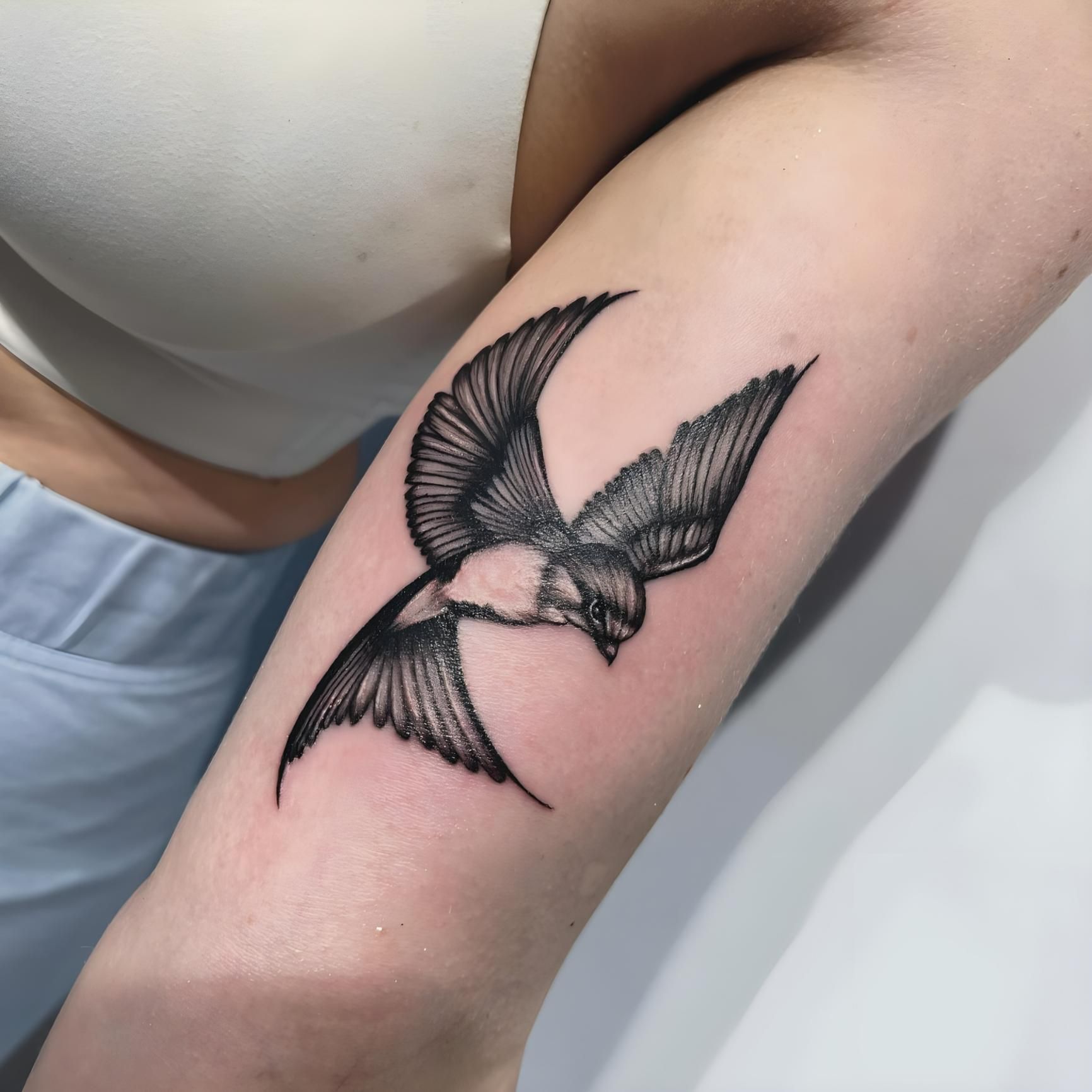 Black and white bird tattoo on a person's forearm, wings spread in flight — Tattoo Inc Studio In Broadbeach, QLD