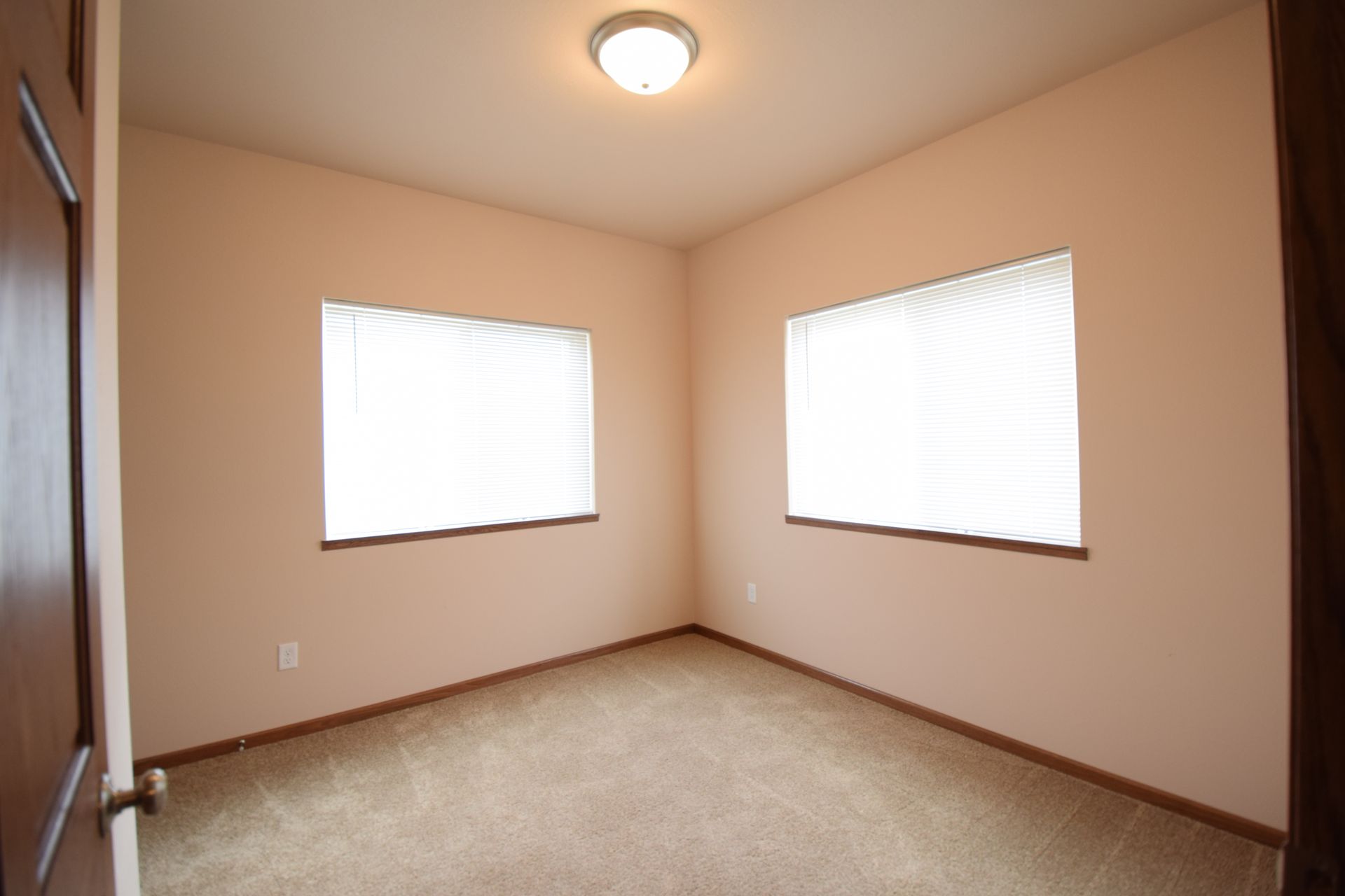 an empty room with two windows and a light on the ceiling