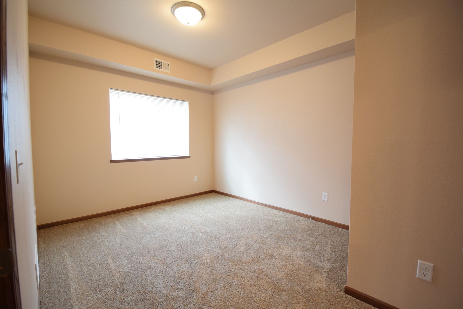 an empty room with a window and a light on the ceiling