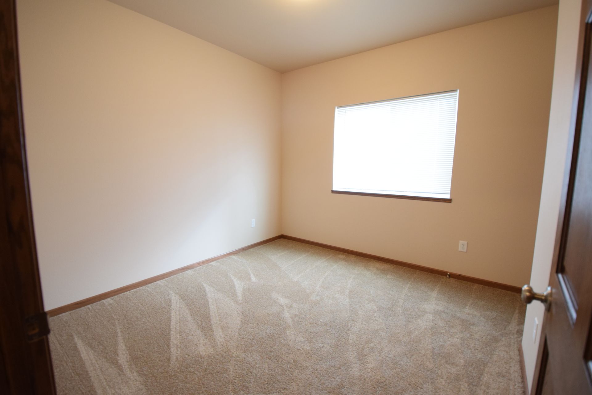 an empty bedroom with a window and blinds