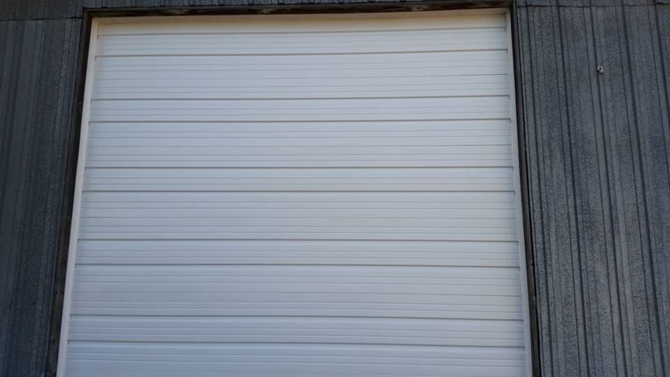 A white garage door is sitting on a wooden wall.