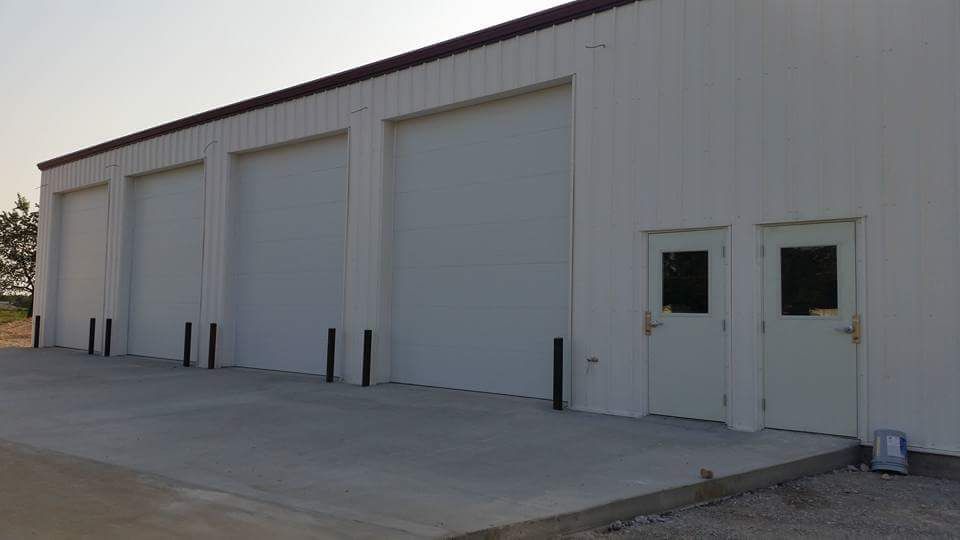 A white building with a lot of garage doors and doors.