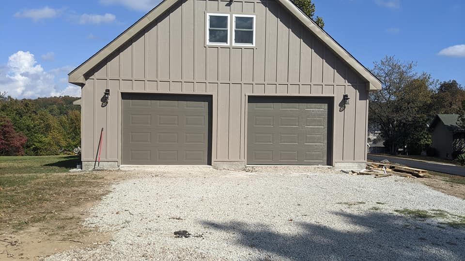 A garage with two garage doors and a driveway in front of it