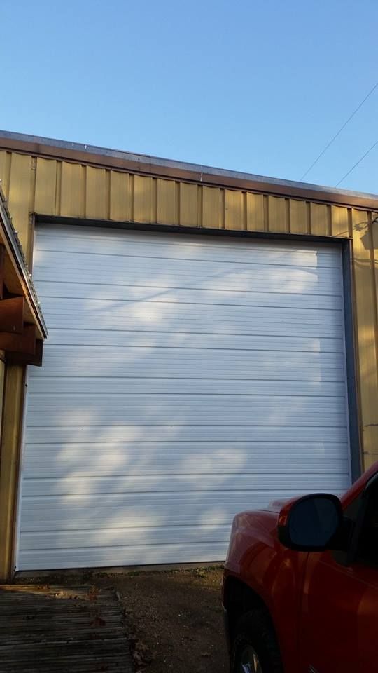 A red truck is parked in front of a white garage door.