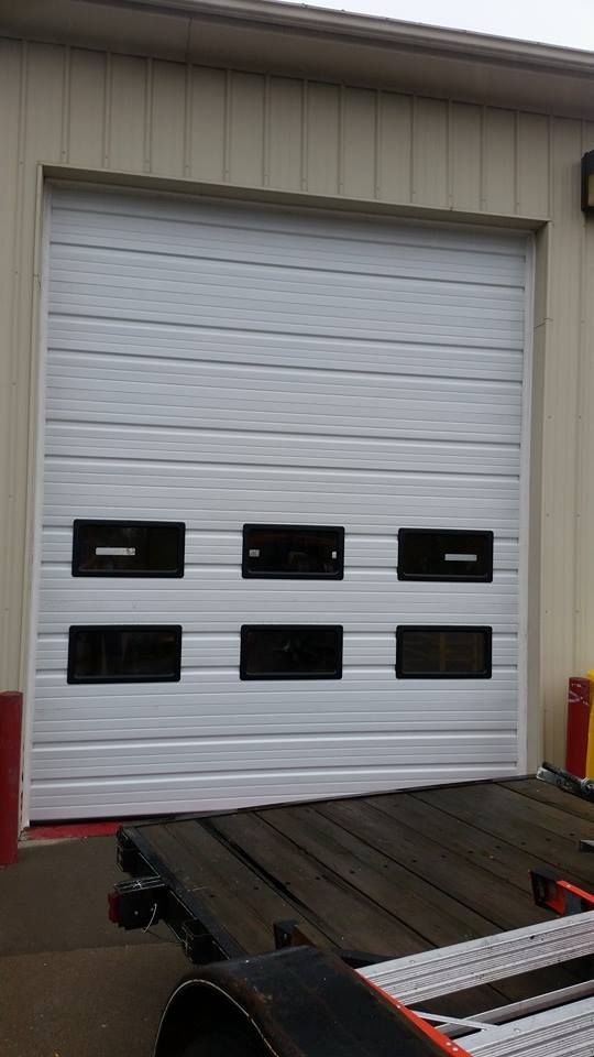 A white garage door with a trailer parked in front of it.