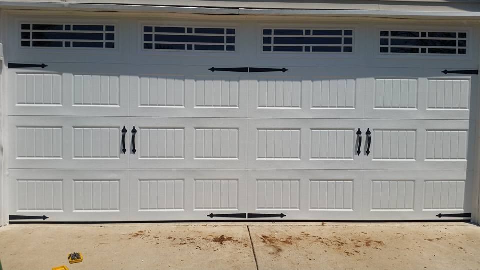 A white garage door with black handles is sitting on top of a concrete driveway.