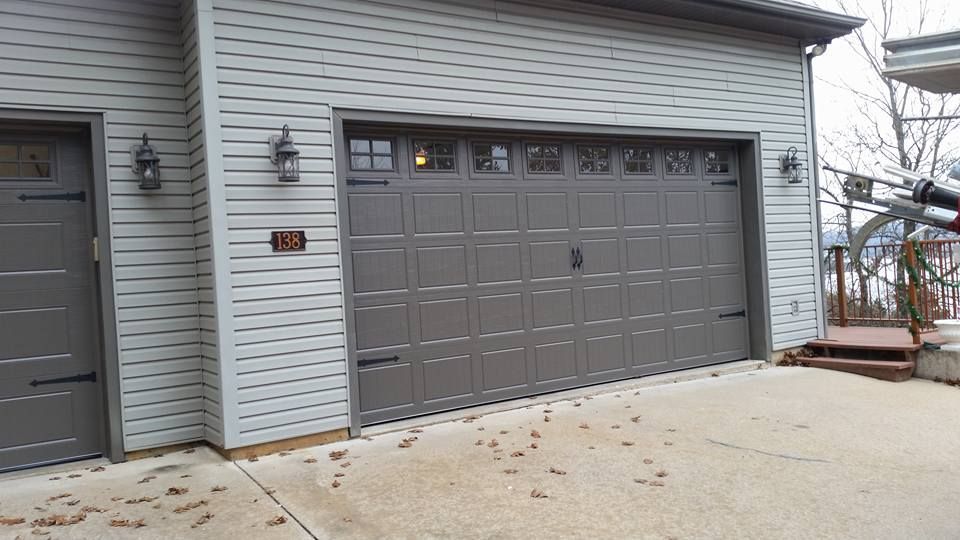 A white house with two garage doors and a concrete driveway.