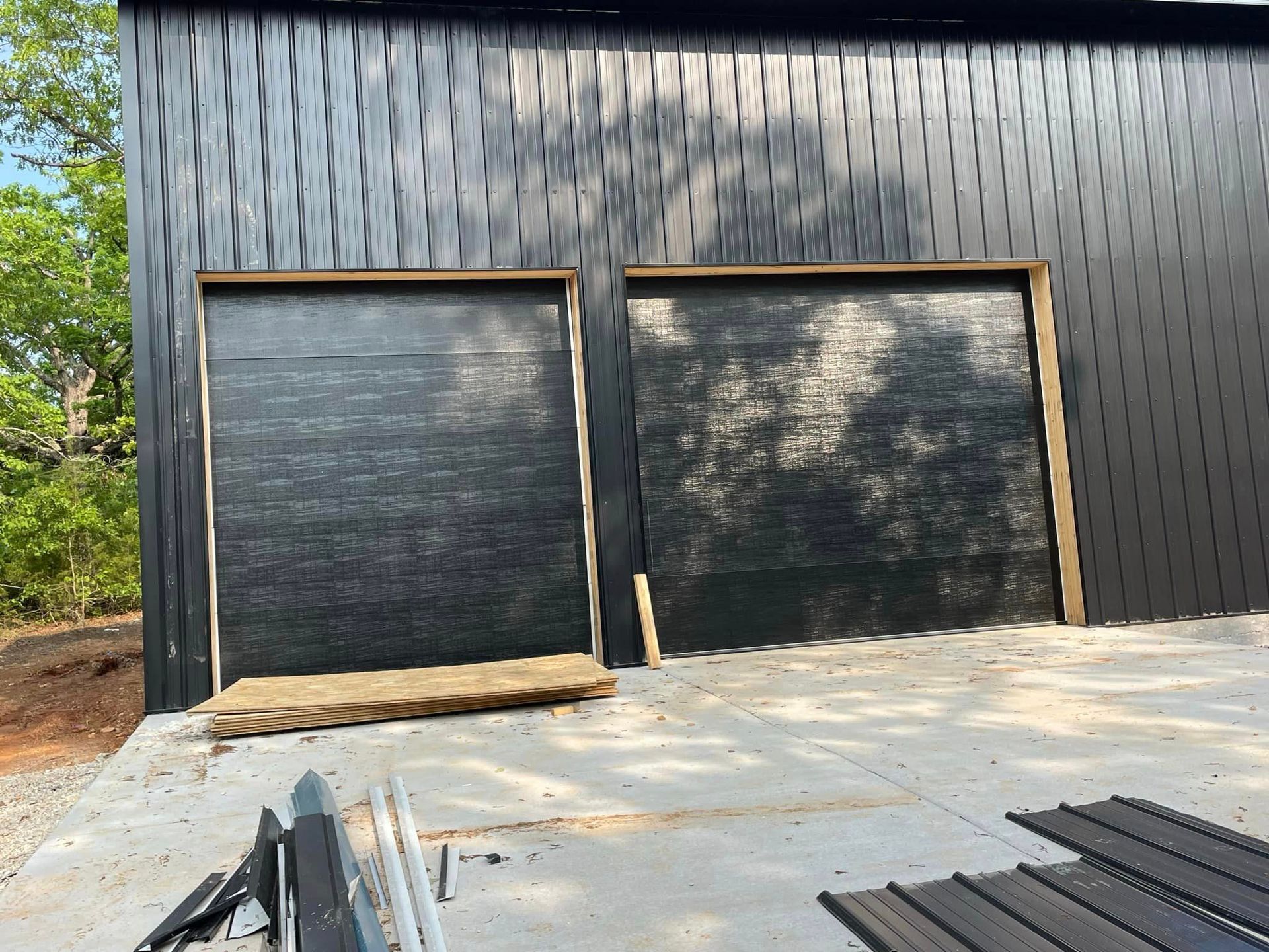 A black garage door is being installed on the side of a building.