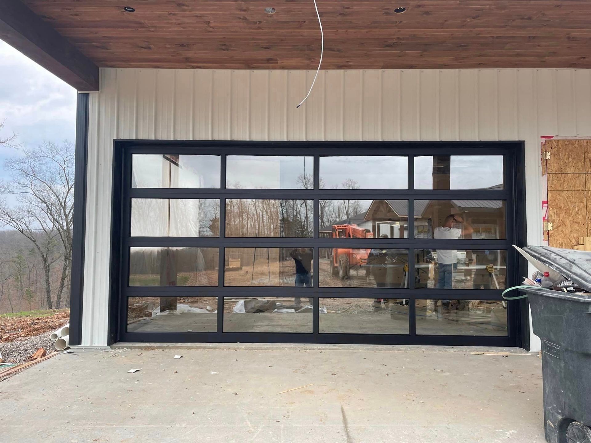 A garage door with a lot of windows and a trash can in front of it.