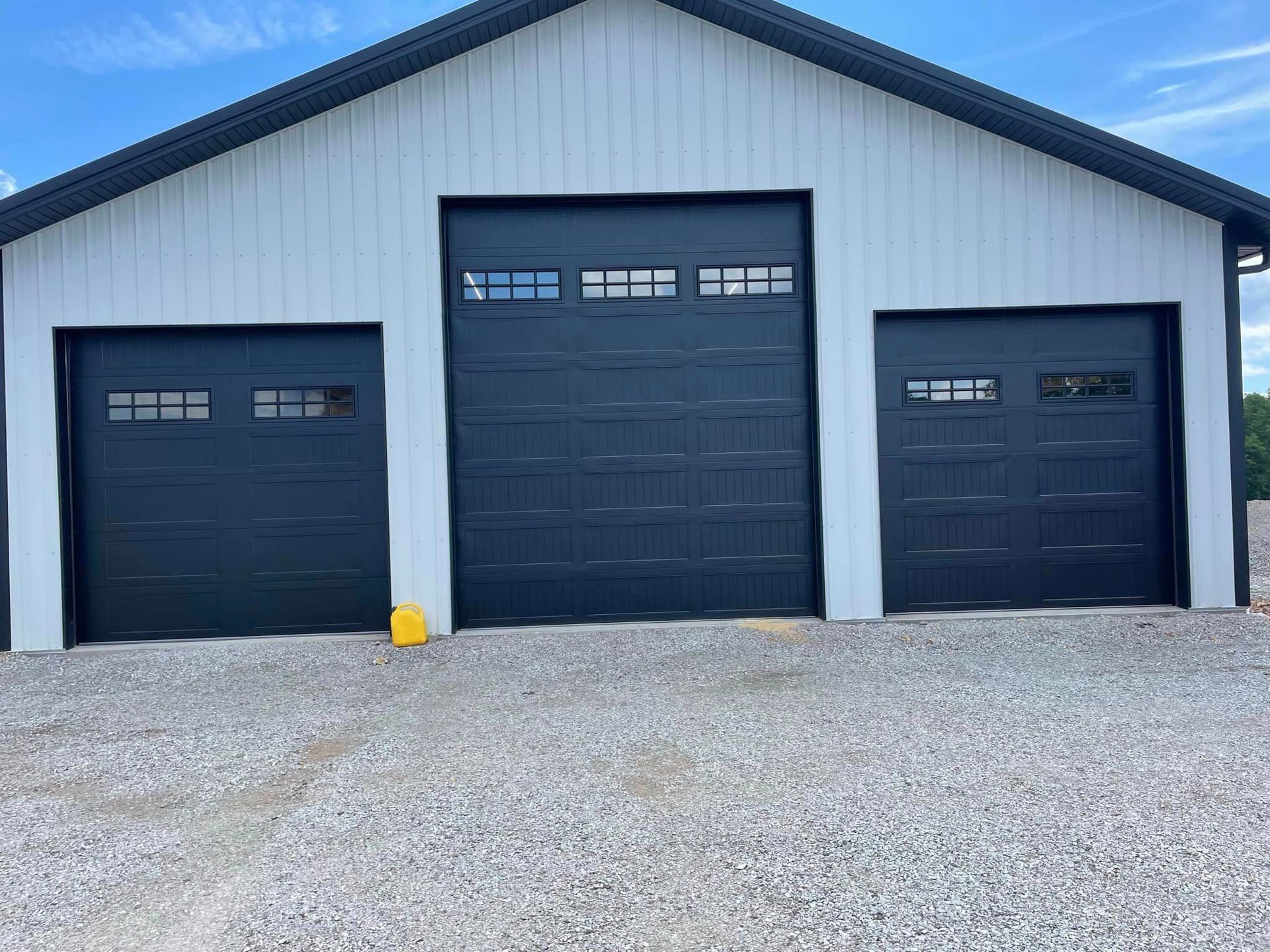 A white and black garage with three black garage doors.